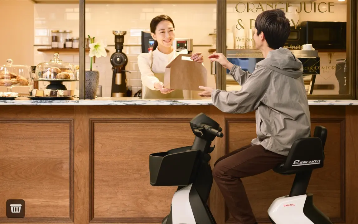 画像：コーヒースタンドでテイクアウトを受け取る、e-SNEAKERに乗った男性