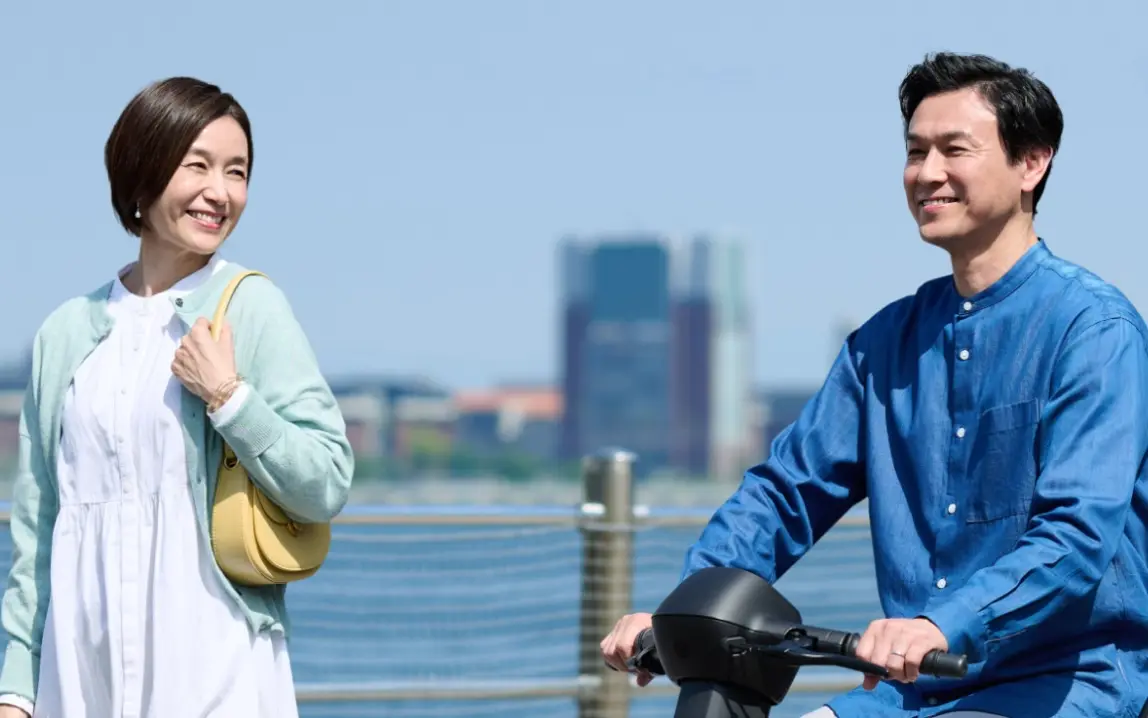 画像：海が見える歩道でe-SNEAKERに乗る男性と隣を歩く女性